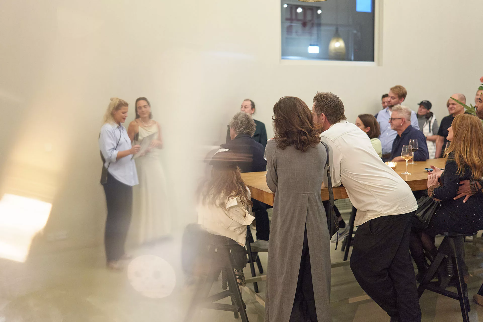 Eine Gruppe von Menschen steht und sitzt bei einer Veranstaltung in einem modernen Raum, während sie zuhören.