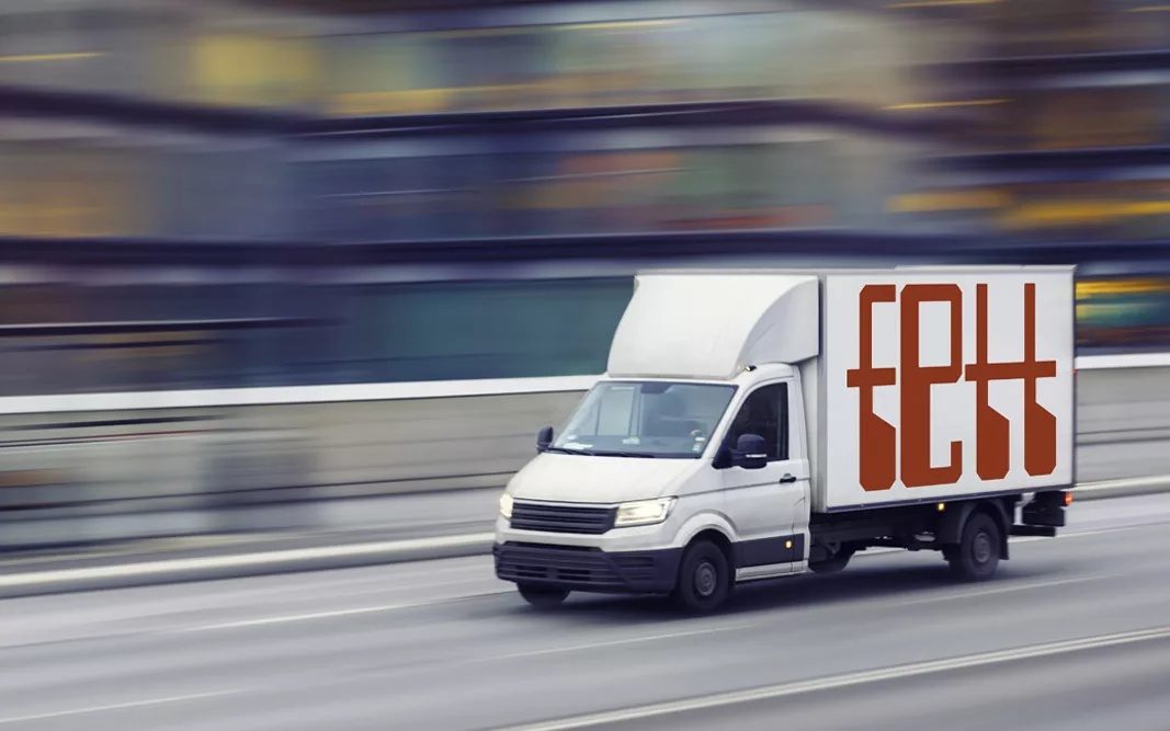 Fast delivery truck travelling through the city streets Lieferwagen fährt schnell auf Stadtstraße, mit rotem Logo Fett an der Seite. Hintergrund in Bewegungsunschärfe.