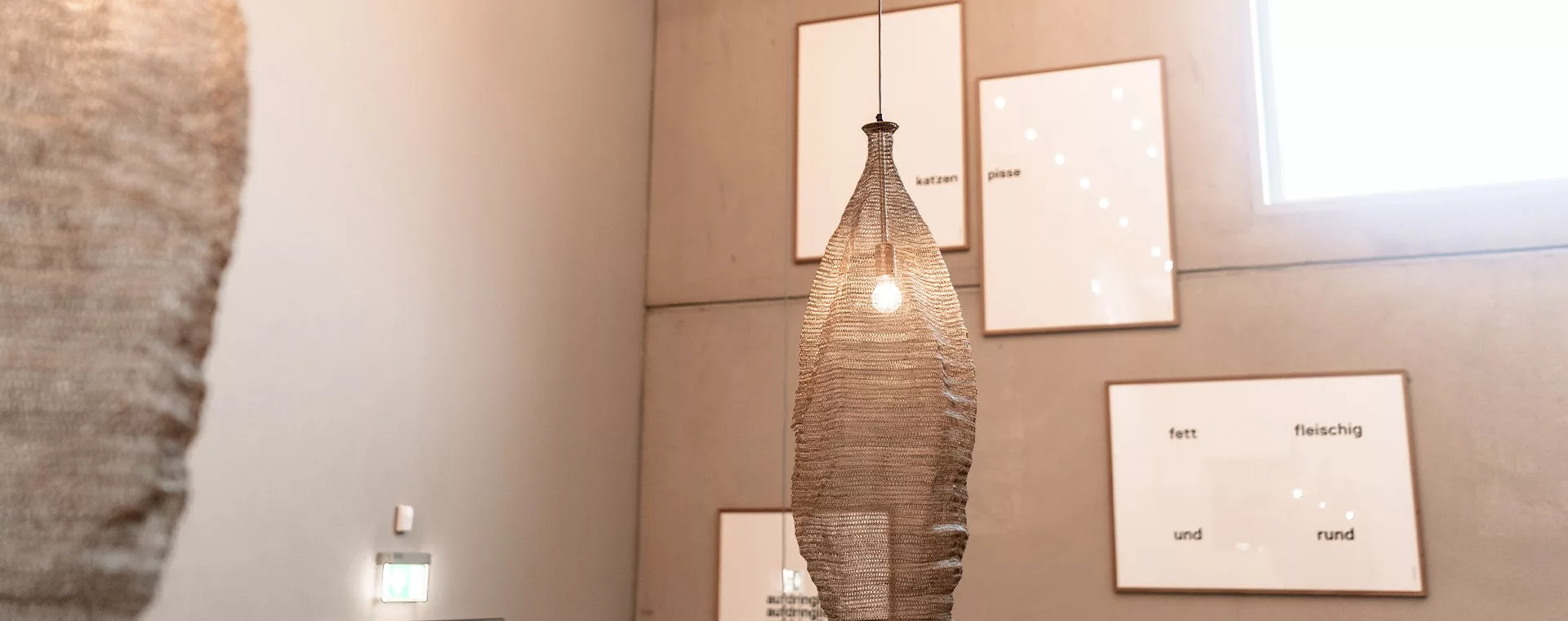 Hängelampe im modernen Raum mit Textbildern an der Wand, darunter Begriffe wie katzen und fett fleischig.